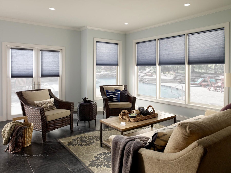 Lutron shades are halfway down in a living room overseeing a pool. 