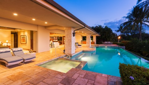A pool area in a luxury beach home illuminated with beautiful lighting fixtures.