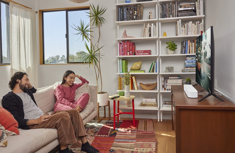 Man and woman watch a movie in a living room with a Sonos soundbar.
