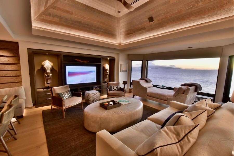 media room with wall-mounted TV display and floor-to-ceiling windows overlooking the ocean.
