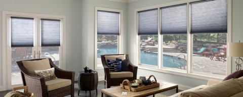 Lutron shades on large floor-to-ceiling windows overlooking a backyard pool scene