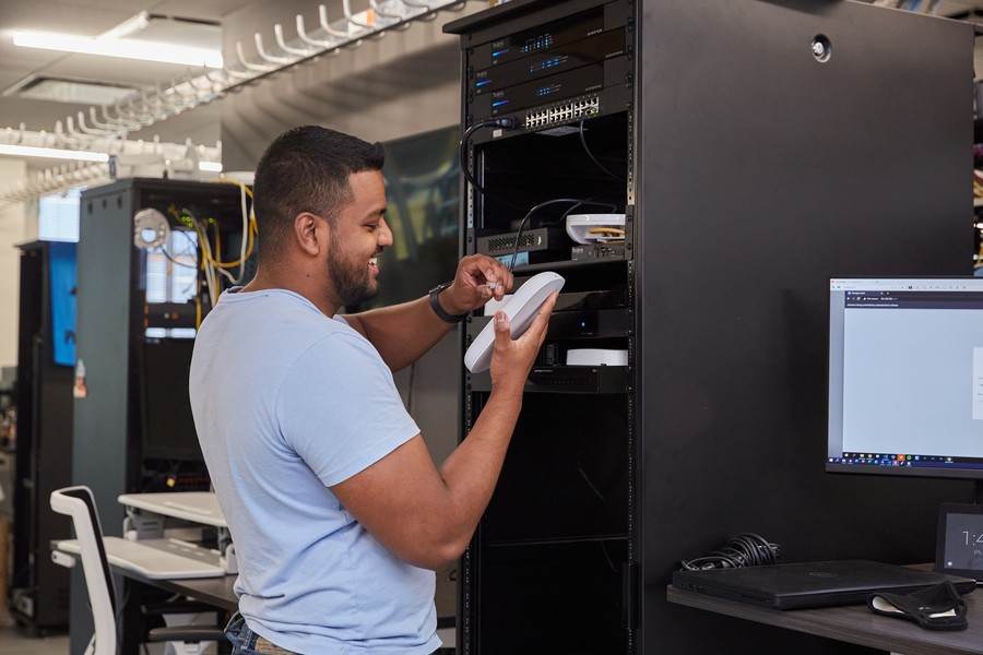 A technician installs a wireless access point in a server rack while working on a smart home installation.